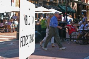 Yield to pedestrians sign with people walking by